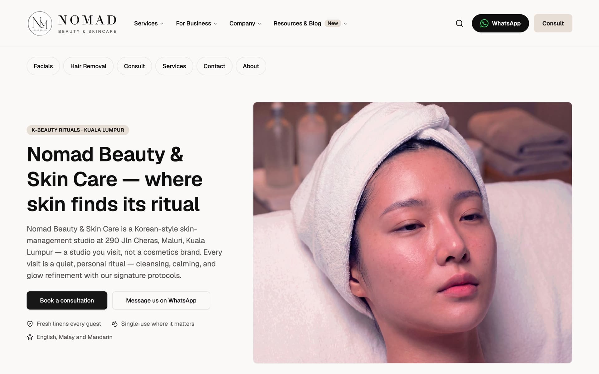 NOMAD Beauty & Skin Care home page on a desktop screen, showing the English version with the Book a consultation and Message us on WhatsApp buttons.